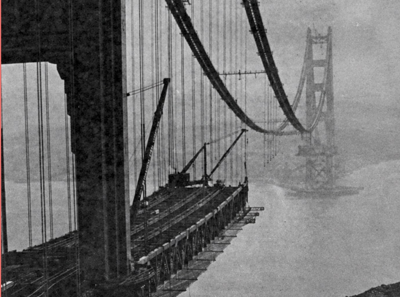The Golden Gate Bridge under construction, roadway sections being laid from the tower with the far tower in fog